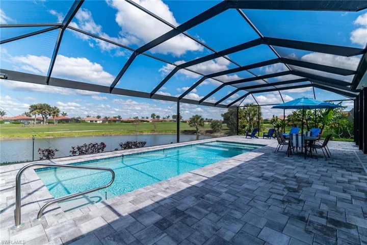 Outdoor pool with a patio, a water view, and glass enclosure