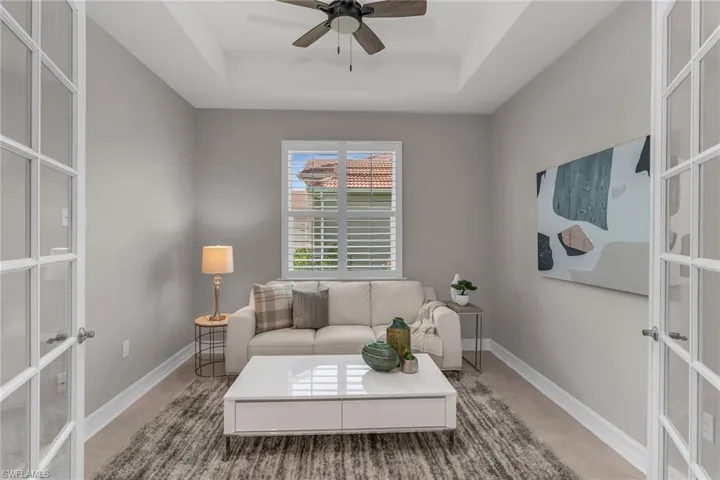 Living room with french doors, a raised ceiling, and light tile patterned floors