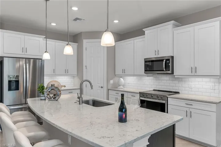 Kitchen featuring a breakfast bar area, stainless steel appliances, visible vents, a kitchen island with sink, and a sink