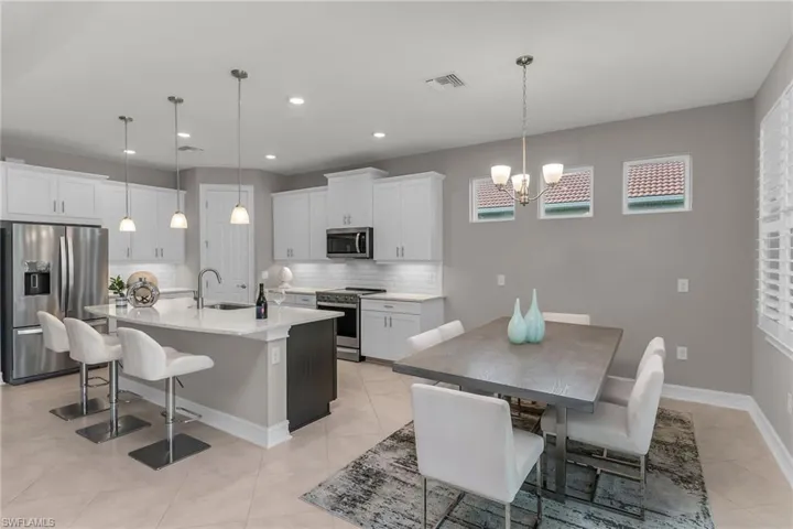 Kitchen featuring visible vents, an island with sink, appliances with stainless steel finishes, a kitchen bar, and a sink