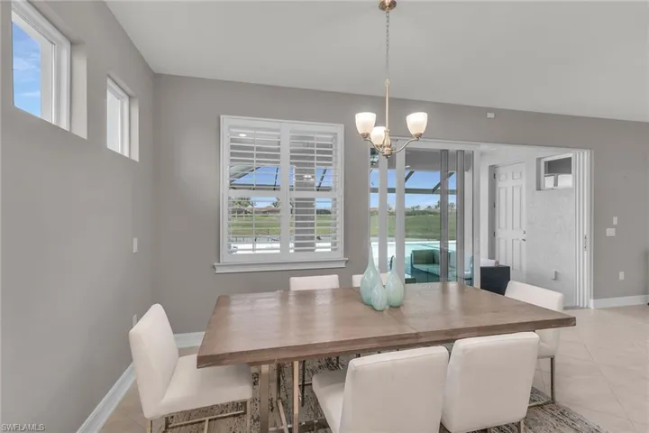 Dining room featuring a healthy amount of sunlight, light tile patterned floors, and a notable chandelier
