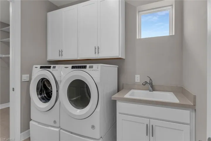 Laundry area featuring washing machine and dryer, cabinet space, and a sink