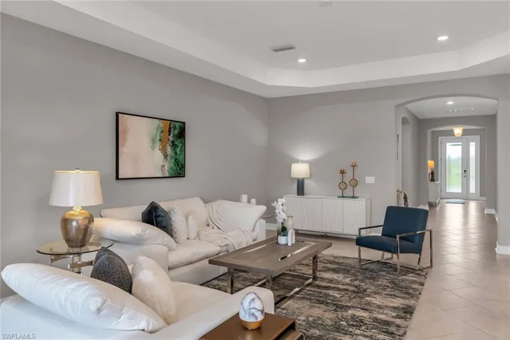 Living area with visible vents, arched walkways, radiator, light tile patterned flooring, and recessed lighting