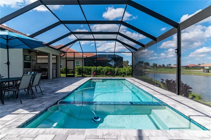 View of pool featuring a patio, a water view, a lanai, and a pool with connected hot tub