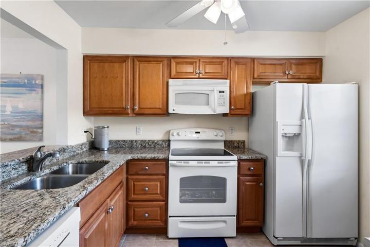 Kitchen offers white appliances and warm granite countertops.