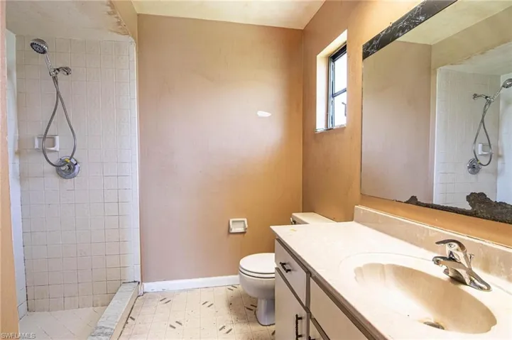Bathroom with vanity, toilet, tile patterned floors, and a tile shower