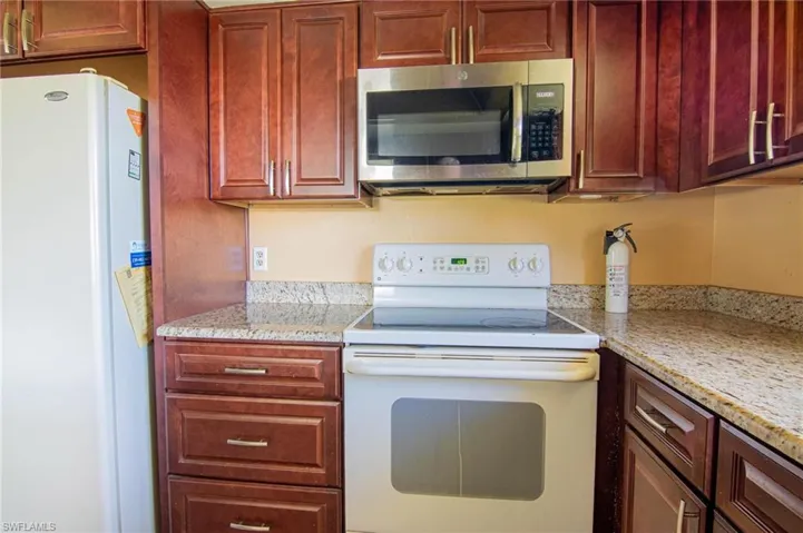 Kitchen featuring light stone counters and white appliances