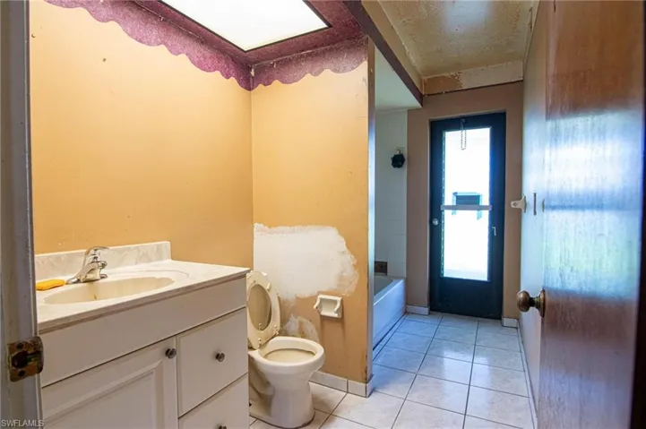 Full bathroom featuring vanity, tile patterned floors, washtub / shower combination, and toilet