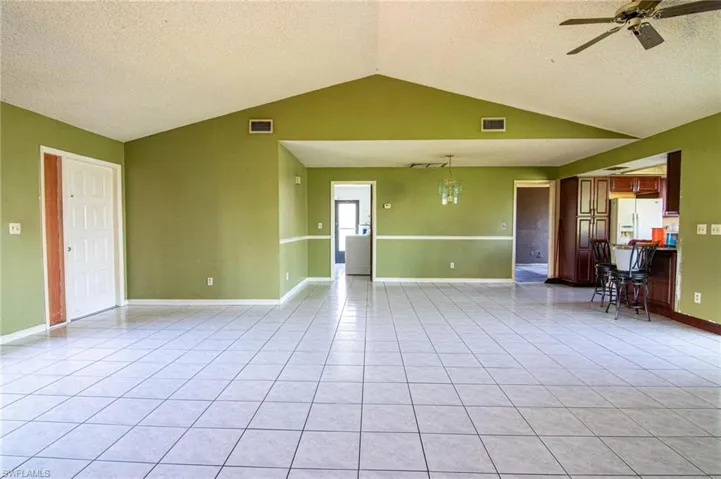 Tiled spare room with a textured ceiling, lofted ceiling, and ceiling fan