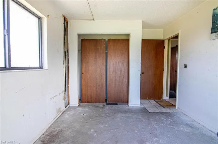 Unfurnished bedroom with concrete floors, multiple windows, a closet, and a textured ceiling