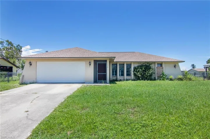 Ranch-style house featuring a garage and a front yard
