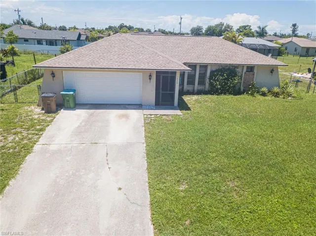 Single story home with a garage and a front lawn