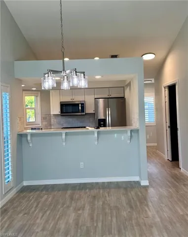 Kitchen featuring a breakfast bar area, stainless steel appliances, a peninsula, vaulted ceiling, and decorative backsplash