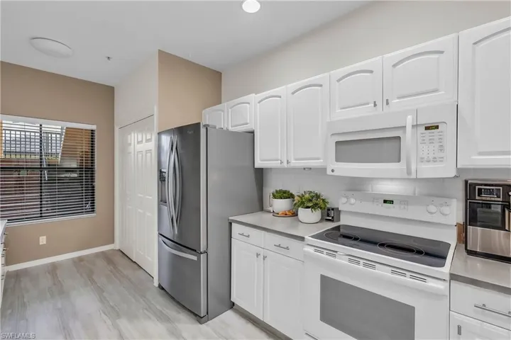 Kitchen with decorative backsplash, white appliances, light wood-type flooring, and white cabinetry