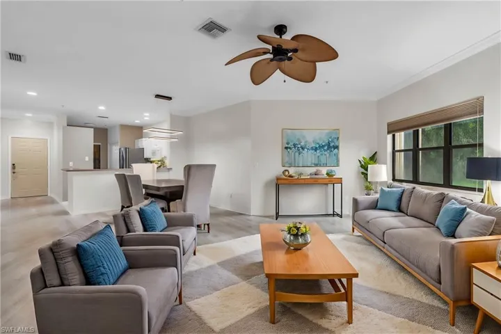 Living room with ornamental molding, light wood-type flooring, and ceiling fan