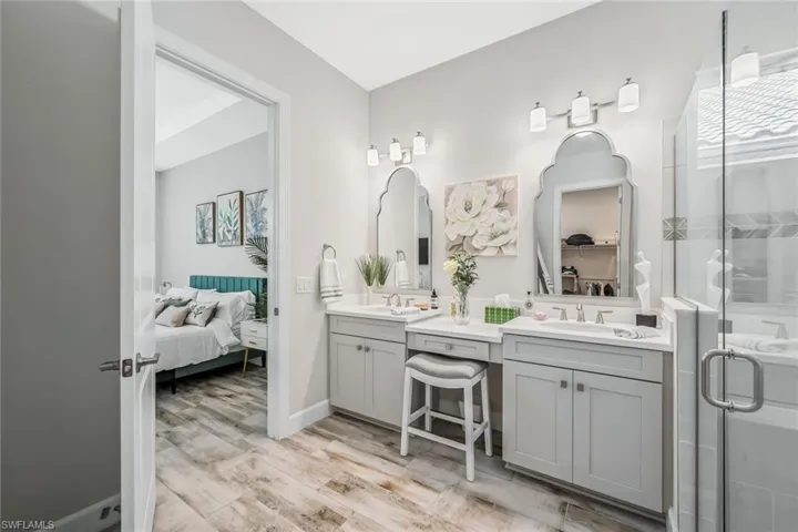 Full bathroom with double vanity, ensuite bathroom, wood finished floors, and a shower stall
