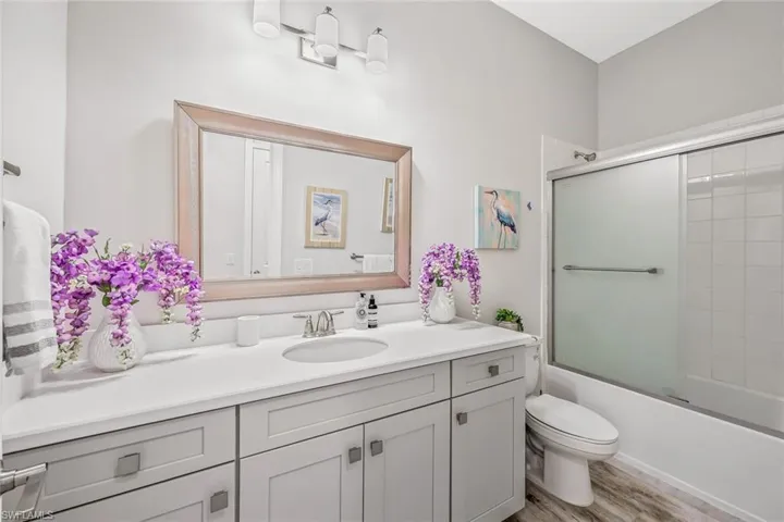 Full bath featuring vanity, shower / bath combination with glass door, and wood finished floors