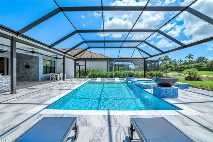 View of swimming pool with a patio, a ceiling fan, glass enclosure, and a pool with connected hot tub