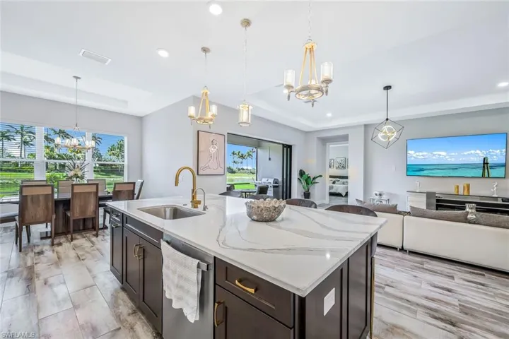 Kitchen featuring a chandelier, stainless steel dishwasher, a raised ceiling, open floor plan, and recessed lighting