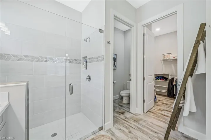 Full bathroom with a stall shower, wood finished floors, a walk in closet, and vanity