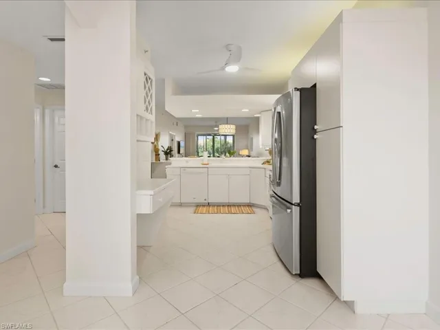 Kitchen featuring white cabinets, freestanding refrigerator, light countertops, light tile patterned floors, and decorative light fixtures