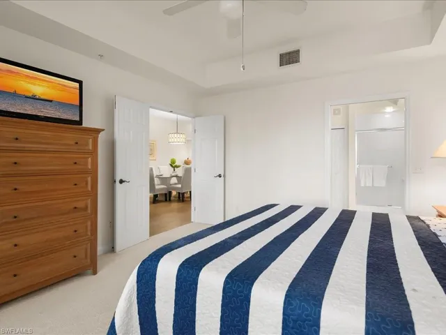 Bedroom with light carpet, ceiling fan, and connected bathroom