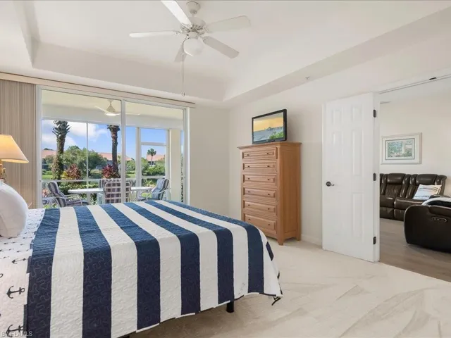 Carpeted bedroom with a raised ceiling, access to exterior, and a ceiling fan