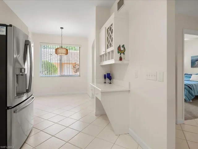 Kitchen featuring stainless steel fridge with ice dispenser, light tile patterned floors, light countertops, decorative light fixtures, and white cabinets