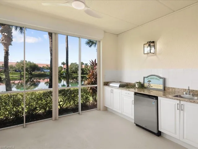 Kitchen featuring light stone countertops, white cabinets, a water view, stainless steel refrigerator, and a wainscoted wall