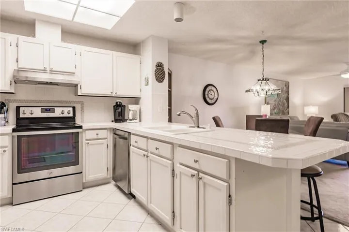 Kitchen featuring stainless steel appliances, decorative backsplash, light countertops, light tile patterned floors, and open floor plan