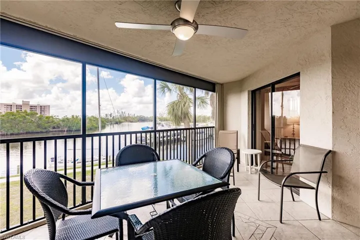 Sunroom / solarium with a water view, a ceiling fan, a balcony, and outdoor dining space