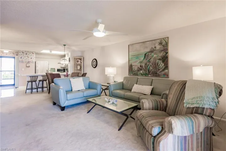 Living area with carpet flooring, a textured ceiling, a ceiling fan, and a chandelier