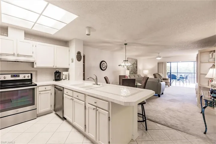 Kitchen with stainless steel appliances, tasteful backsplash, a breakfast bar area, a peninsula, and a textured ceiling
