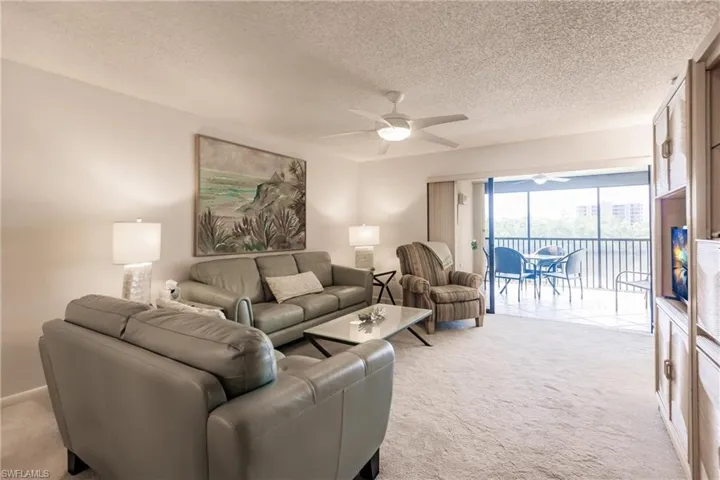 Living area featuring light carpet, a textured ceiling, and ceiling fan