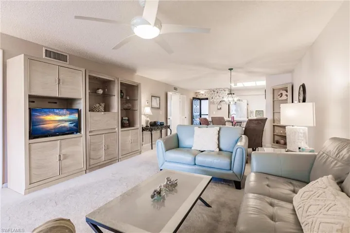 Carpeted living area with a chandelier, ceiling fan, and a textured ceiling