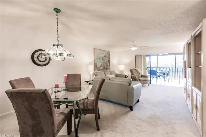 Dining area featuring light colored carpet, a textured ceiling, and ceiling fan