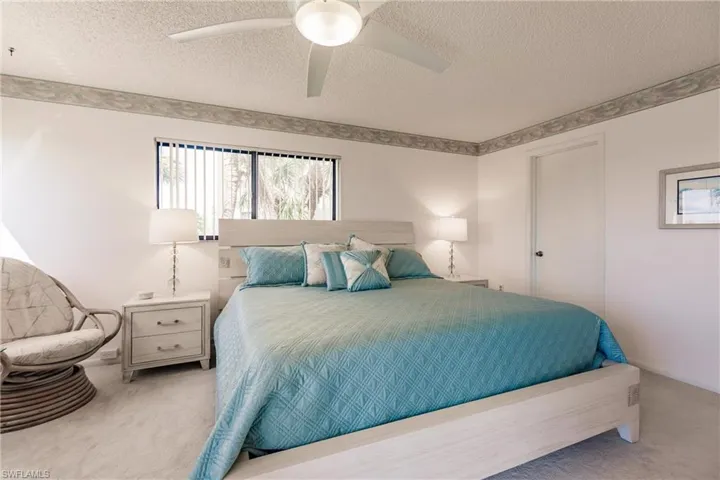 Bedroom with carpet flooring, a textured ceiling, a ceiling fan, and a closet