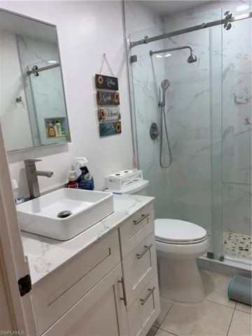 Full bath with vanity, a marble finish shower, and light tile patterned floors