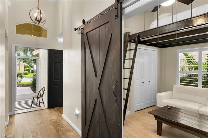 Entryway featuring plenty of natural light, light wood finished floors, a high ceiling, a barn door, and a chandelier