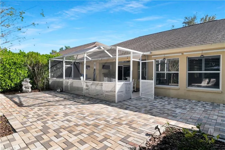 Back of house with glass enclosure, a patio, roof with shingles, and a sunroom