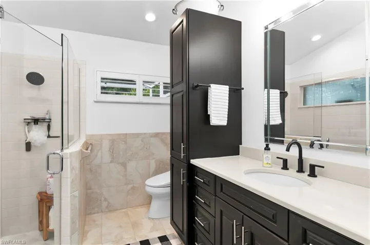 Full bathroom featuring vanity, tile walls, a stall shower, recessed lighting, and light tile patterned flooring