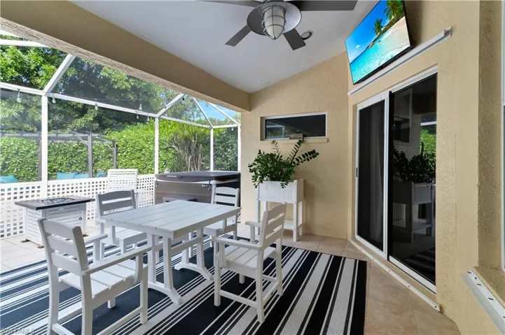 View of patio / terrace with outdoor dining area, a sunroom, a hot tub, a ceiling fan, and a lanai