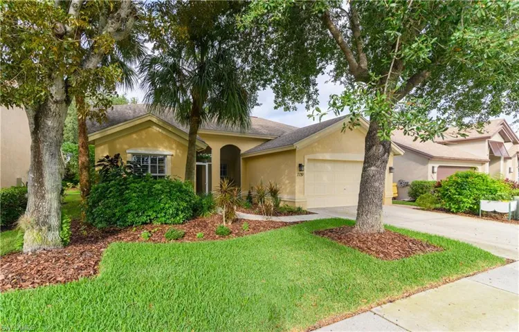 View of front of house with stucco siding, a front yard, driveway, and a garage
