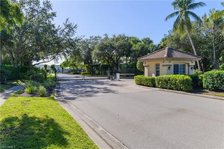 View of asphalt road with curbs, a gated entry, and a gate