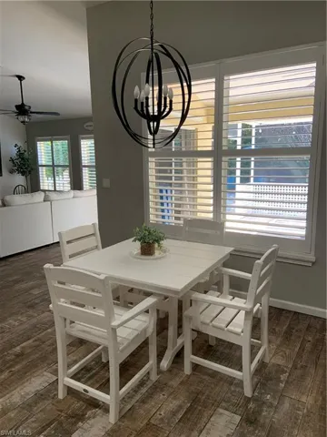 Dining space with dark wood finished floors, a ceiling fan, and a chandelier