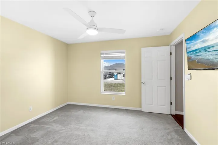 Empty room featuring ceiling fan and light carpet