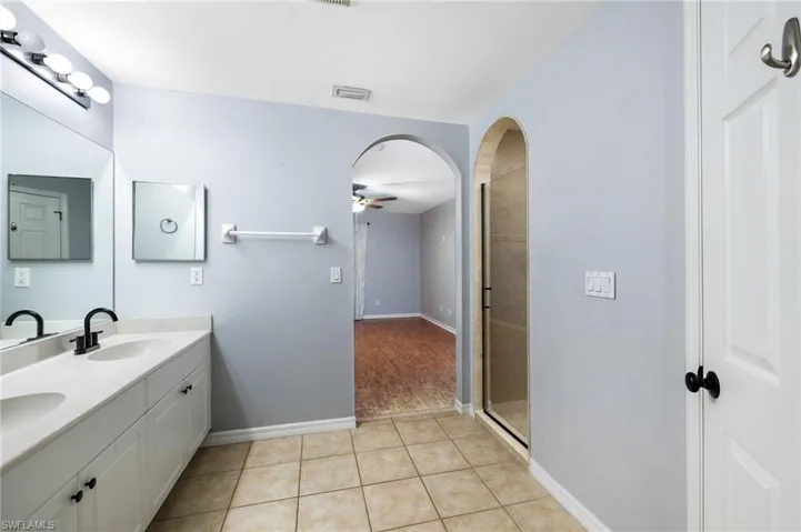 Bathroom featuring tile patterned floors, ceiling fan, vanity, and a shower with shower door