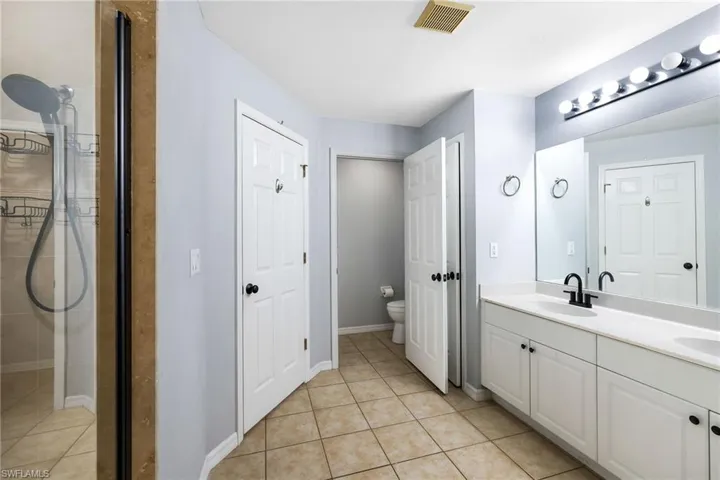 Bathroom featuring tile patterned floors, vanity, toilet, and a shower