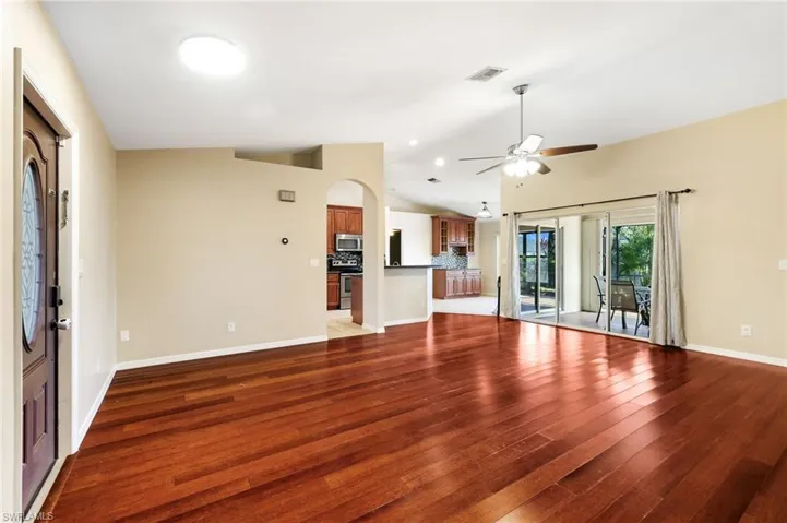 Unfurnished living room with ceiling fan, hardwood / wood-style floors, and vaulted ceiling