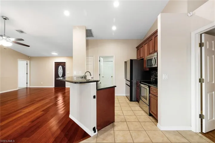 Kitchen featuring dark stone counters, ceiling fan, stainless steel appliances, and light wood-type flooring